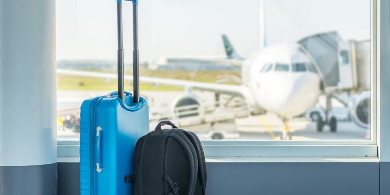 Koffer und Rucksack vor Fenster und Flugzeug